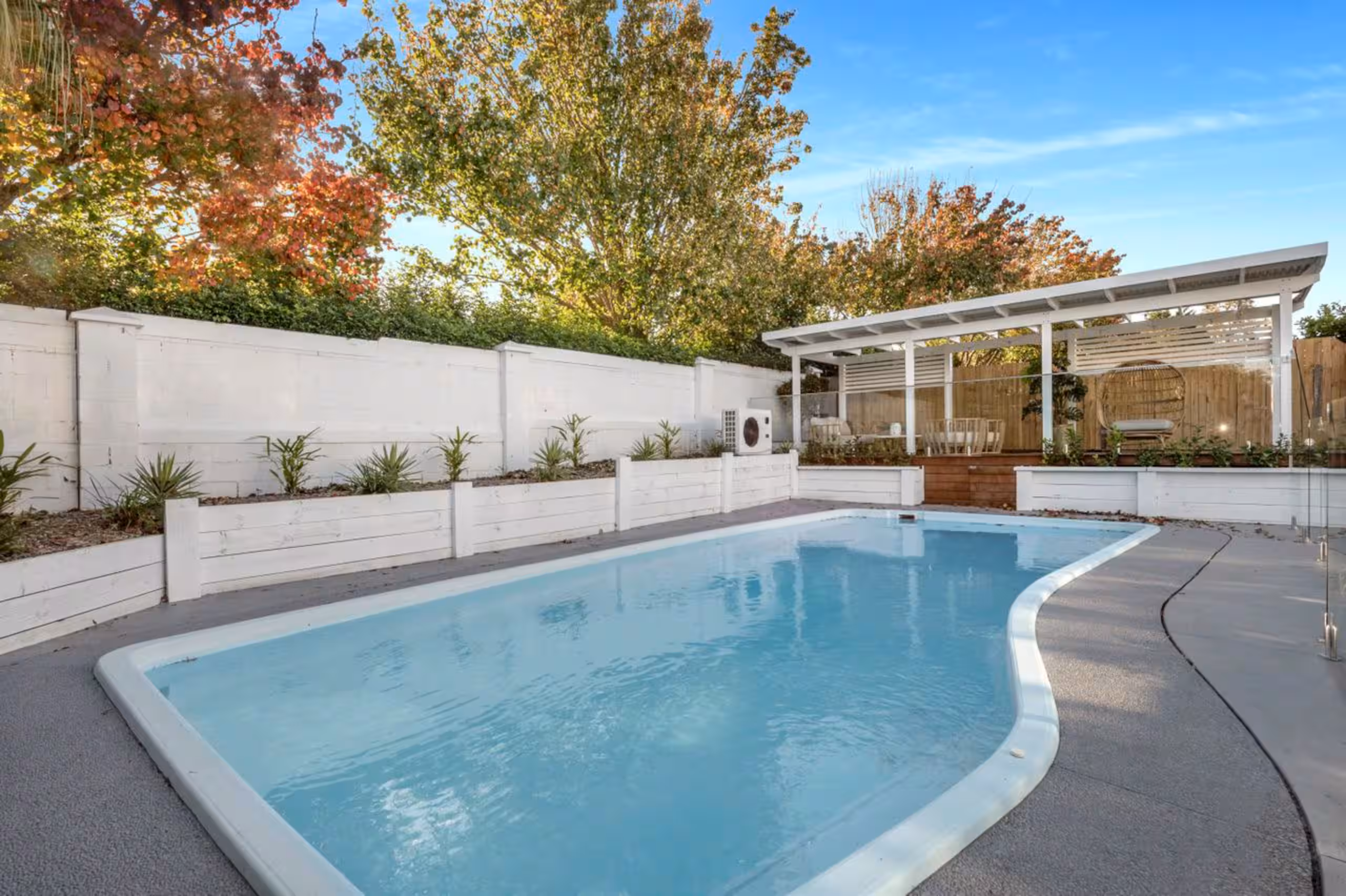 The heated pool and poolside cabana framed by autumn trees.